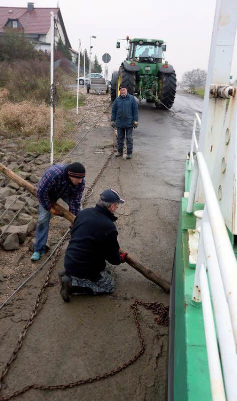 Mitarbeiter der Agrargenossenschaft Pretzsch helfen dabei, die Elbfähre ans Ufer zu schleppen.