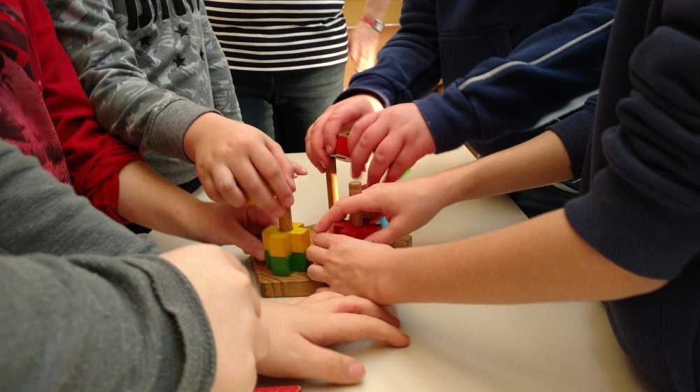 Viele Hände, schnelles Ende? Beim Bauklötzchenstapeln werden den Kindern die Augen verbunden, sie sind ganz auf Tastsinn und Worte angewiesen.