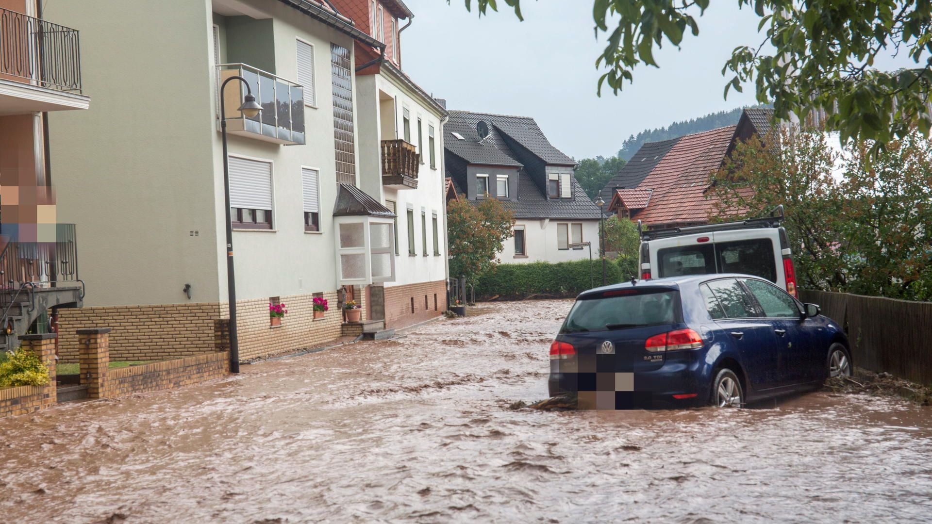Nach Starkregen und Hagelschlag ist eine Straße im hessischern Hetzerode überflutet.