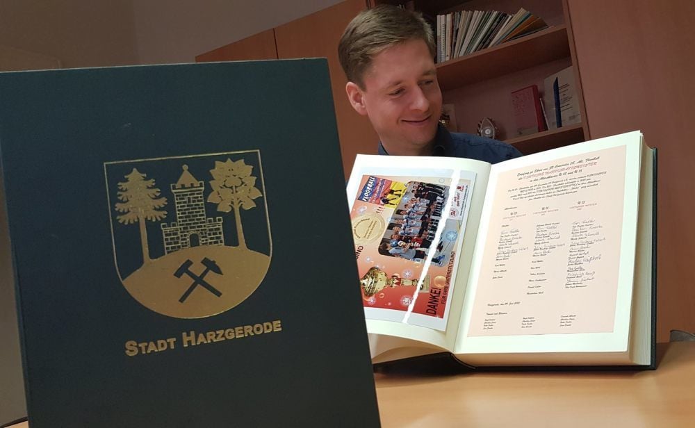 Bürgermeister Marcus Weise blättert im Goldenen Buch der Stadt Harzgerode. Auch die Floorballer verewigten sich darin.