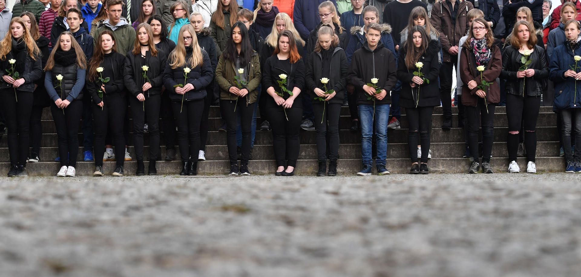 Bei einer Gedenkfeier vor dem Gutenberg-Gymnasium halten Schüler in Erfurt weiße Rosen in den Händen.