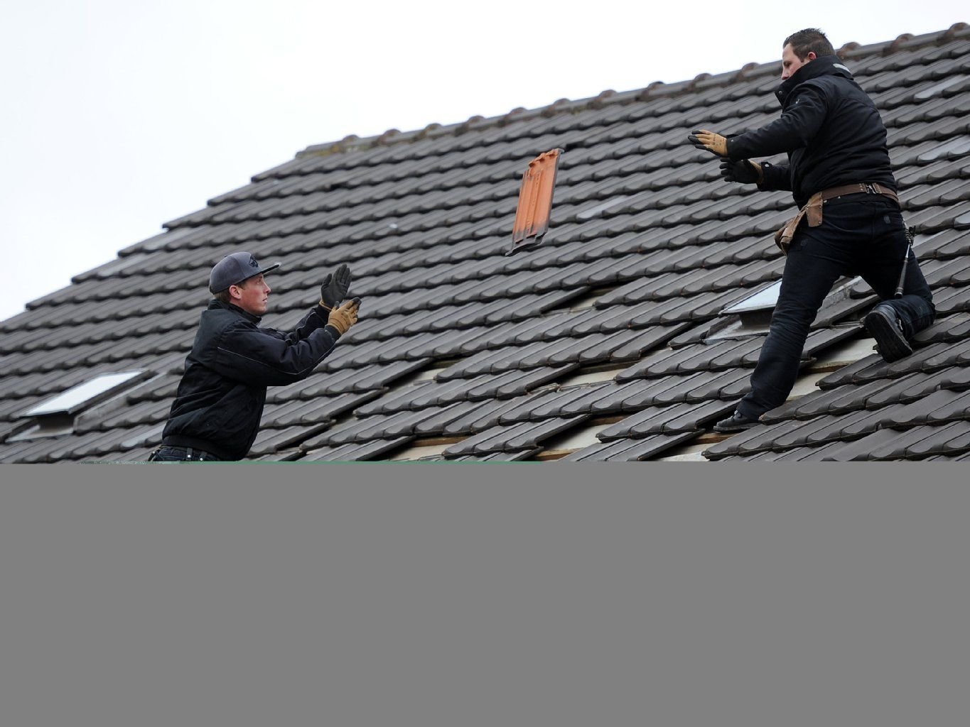 Dachdecker reparieren in Euskirchen (Nordrhein-Westfalen) ein durch die Bombenexplosion am Vortag beschädigtes Hausdach.