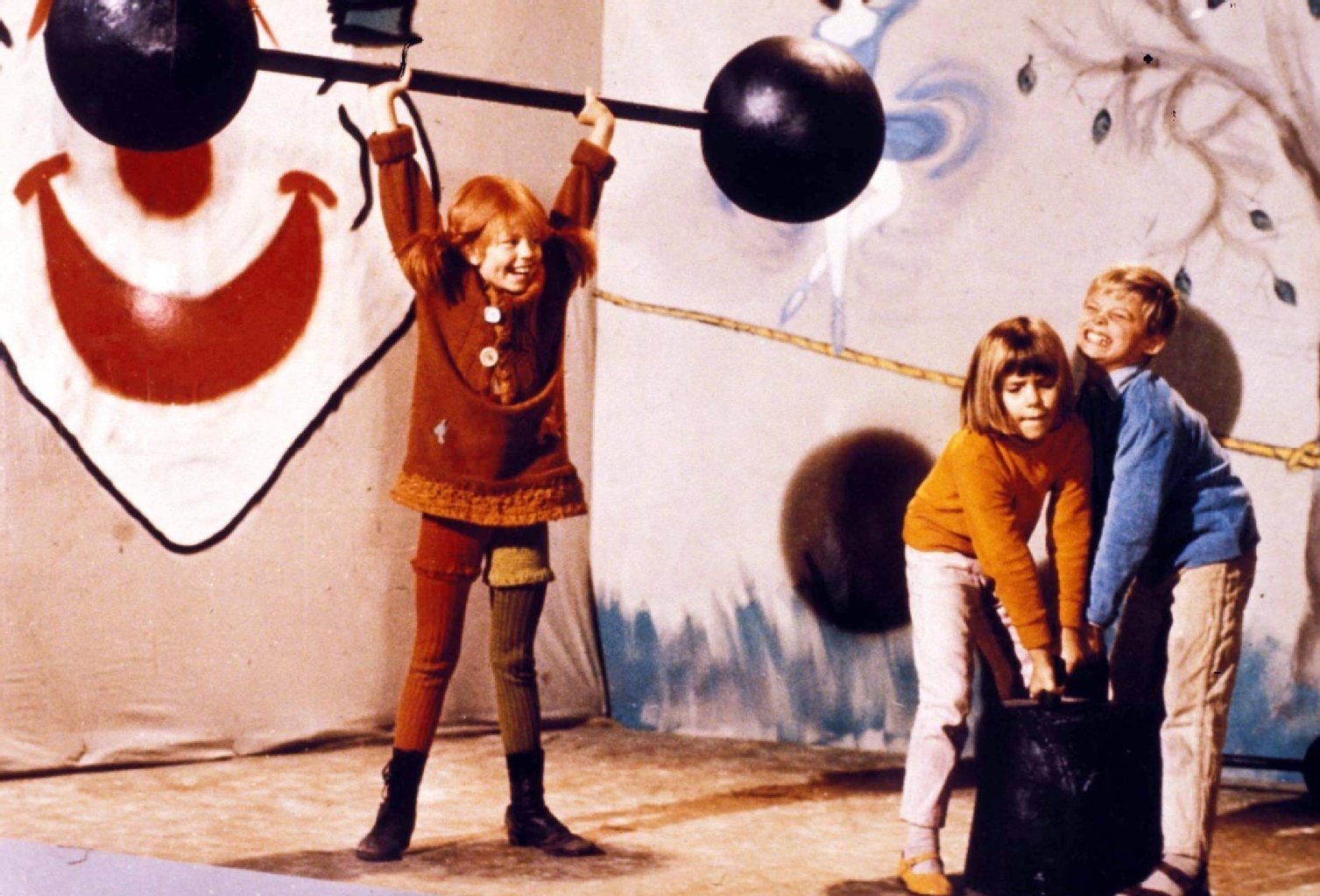 "Boah, ist die stark!" Pippi beeindruckt ihre besten Freunde Tommy und Annika beim Gewichtheben.