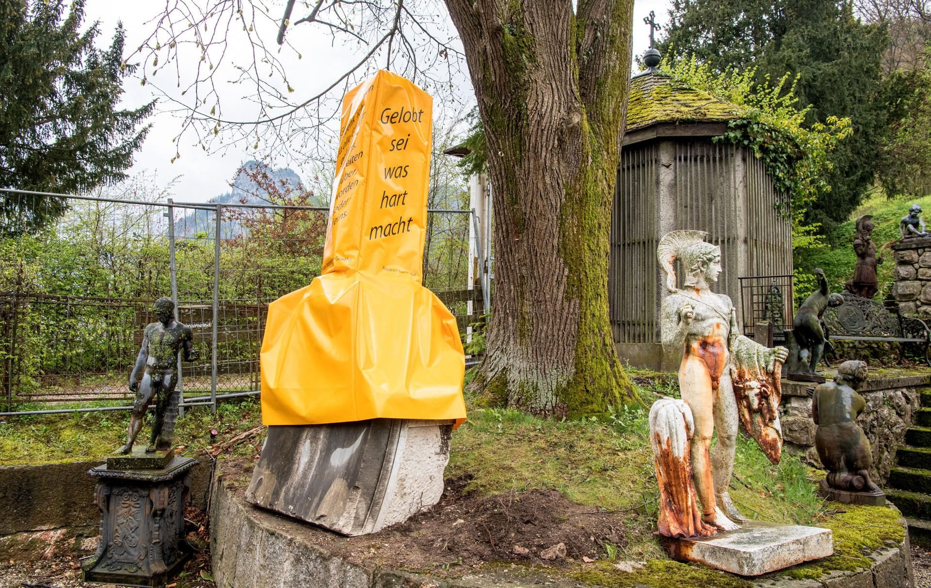 Der steinerne Phallus wird nun mit einer gelben Folie verhüllt.