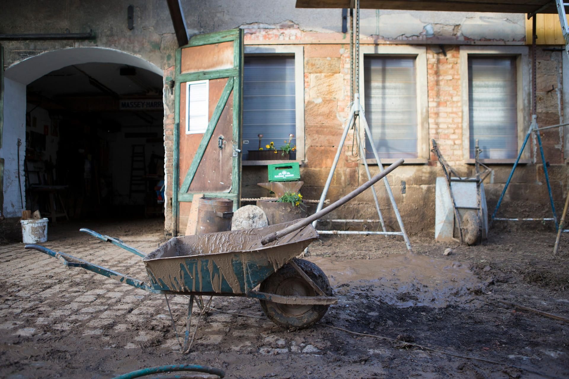 Eine Schubkarre voller Schlamm steht nach einem starken Unwetter vor einem Haus. (Symbolfoto)