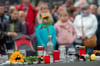 Passanten stehen auf dem Marktplatz in Halle an niedergelegten Blumen und gedenken der Opfer. 