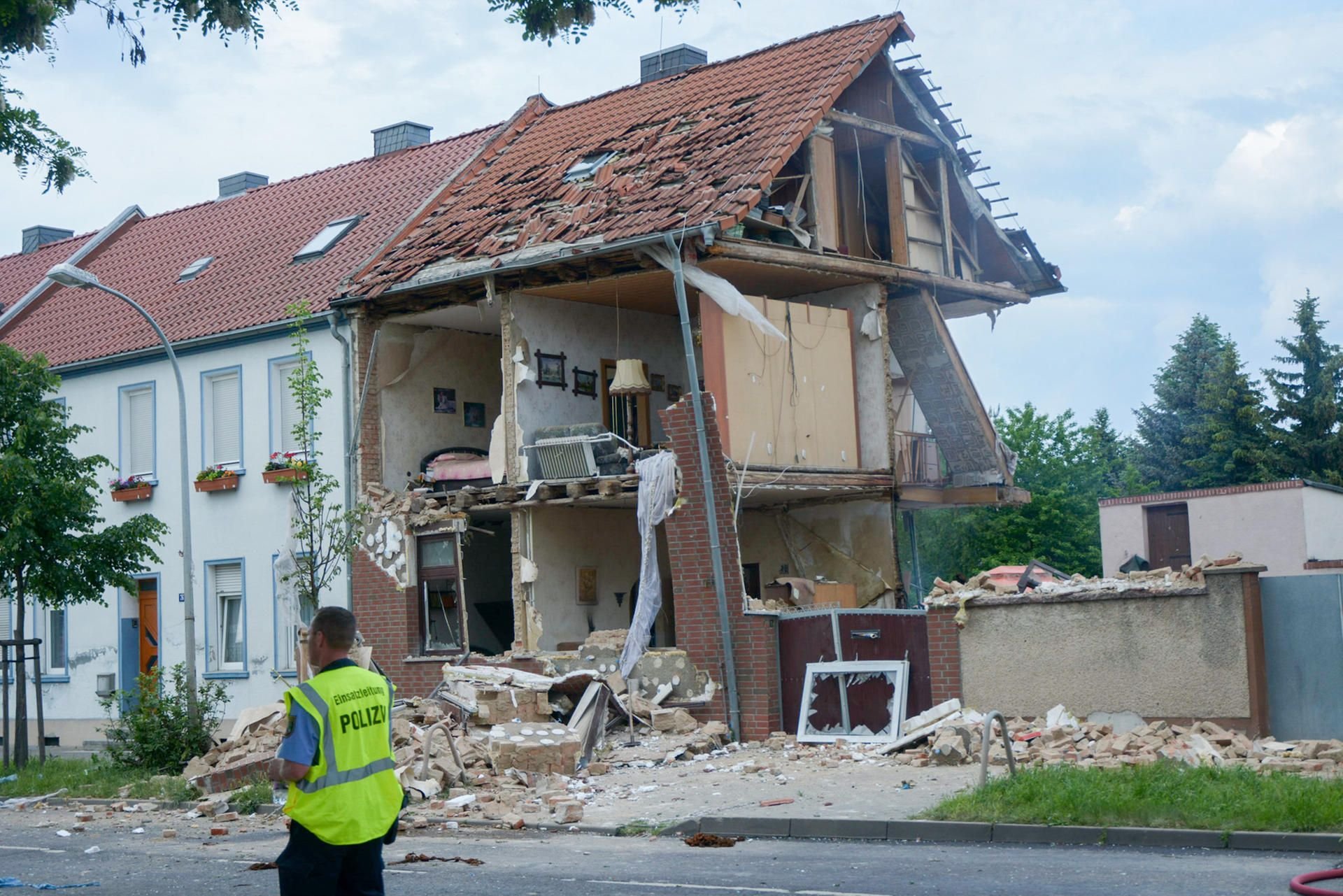 Ein Polizist steht in Schönebeck vor einem schwer beschädigtem Haus.