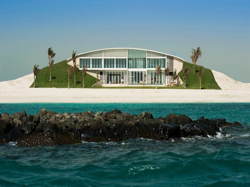 Vom Meer aus gesehen erinnert die mit Kunstrasen und Palmen bepflanzte Ufervilla bei Abu Dhabi an eine halb geöffnete Auster.