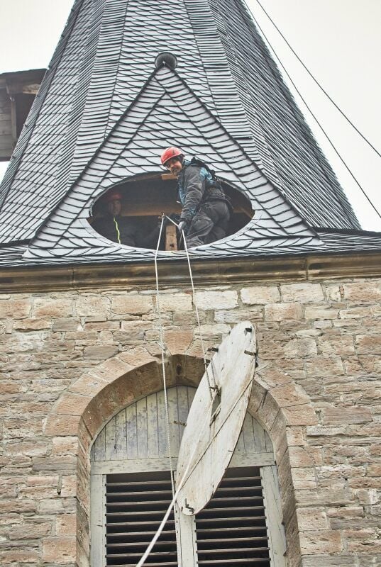 Die Fassadenkletterer Jan Meissner und Ulrich Hörandel (rechts) lassen eines der vier Ziffernblätter aus dem Kirchturm auf den Boden herab.
