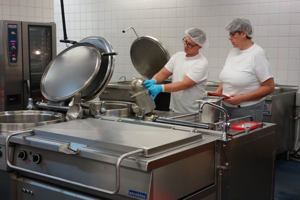 Kevin Müller und die stellvertretende Küchenleiterin Christine Kleppner beim Portionieren.