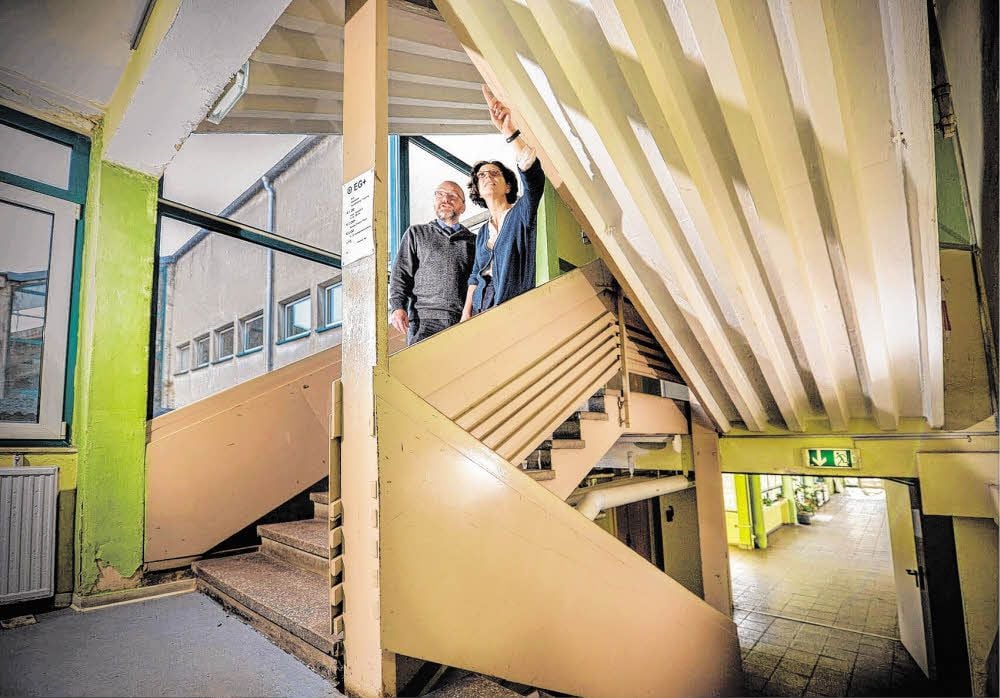 Jochen Muhs und Susan Föhre schauen sich die Schäden im Treppenhaus der Saaleschule an.