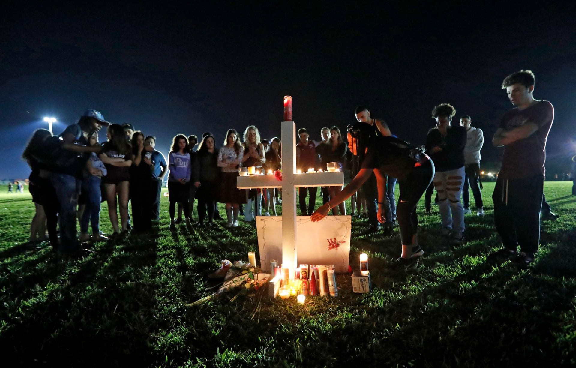 Eine Frau stellt während einer Trauerveranstaltung ein Bild eines der Opfer des Attentats an der Douglas High School an ein mit Kerzen geschmücktes Kreuz.