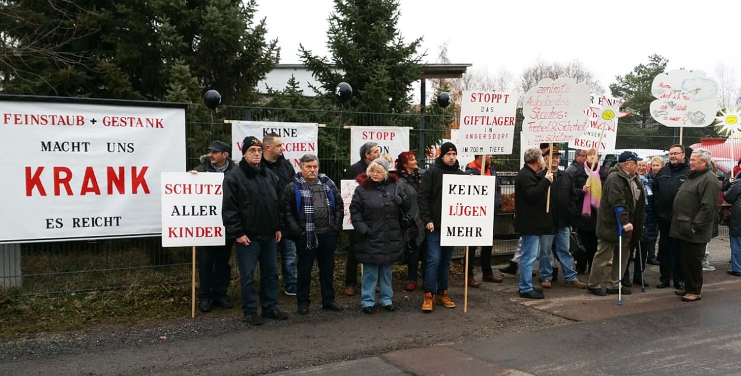 Anwohner mit Schildern und Plakaten gegen Giftmüll und Gestank