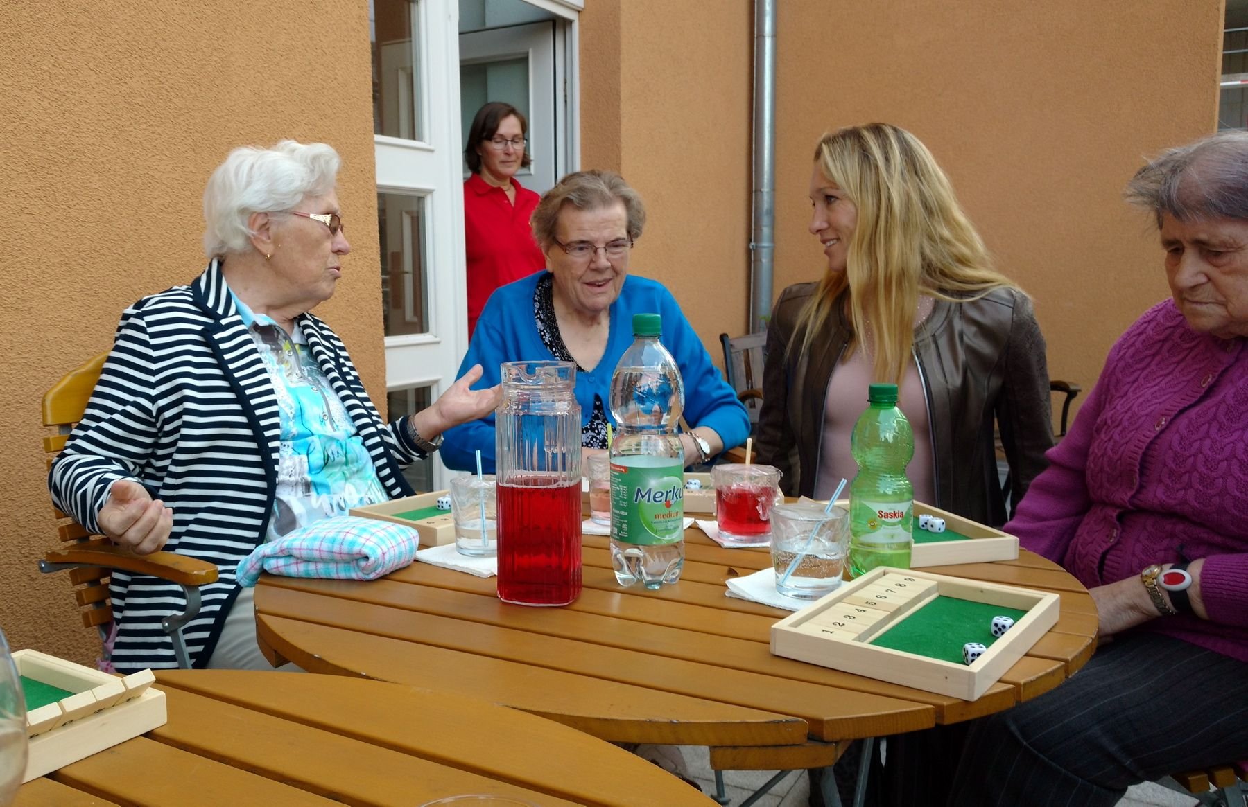 Christine Theiss macht sich ein Bild von der Einrichtung. Auf der Terrasse spielt sie mit Erkrankten Würfelspiele.