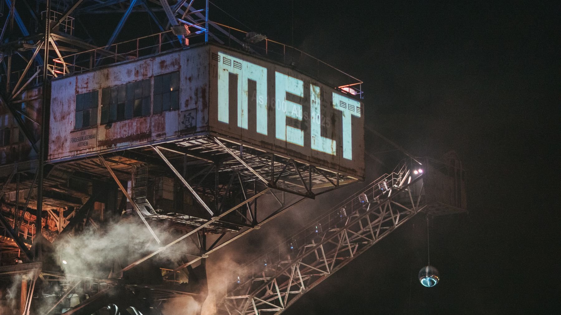Der Schriftzug Melt ist auf das Führerhaus eines  stählernen Baggers projiziert.