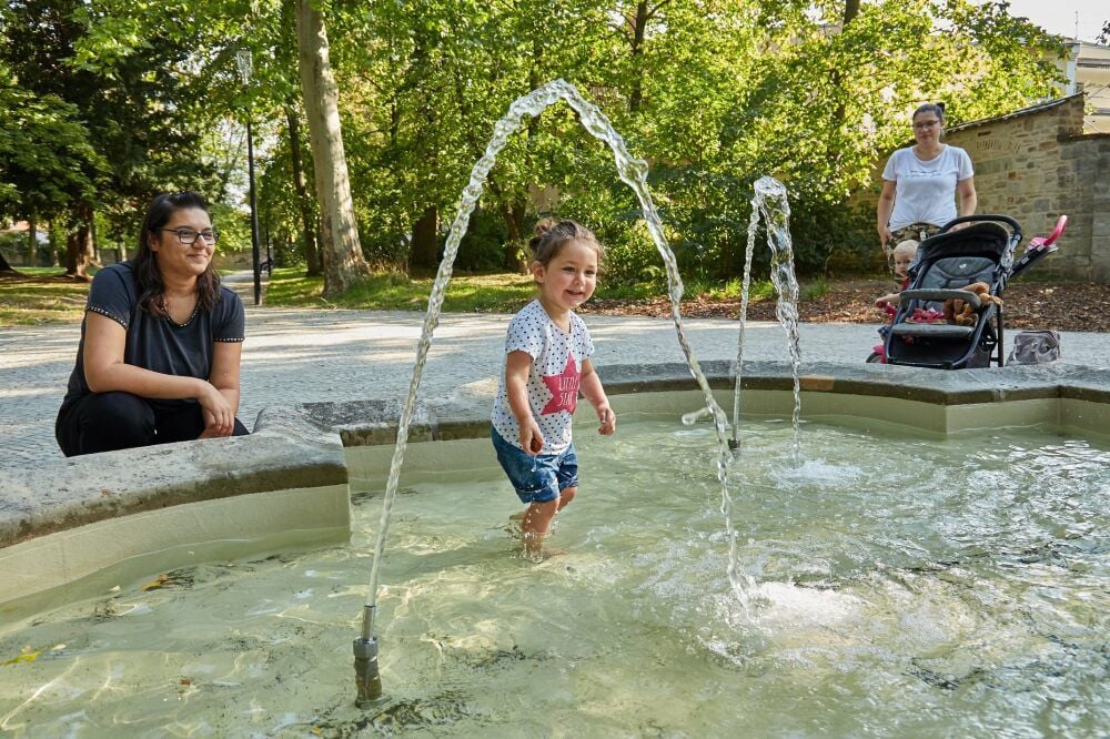 Blerina Tafoshi ist mit Mila (2) zur Erfrischung zum Springbrunnen gekommen. Thore, der Sohn von Kristina Martincik, hält sich noch etwas zurück.