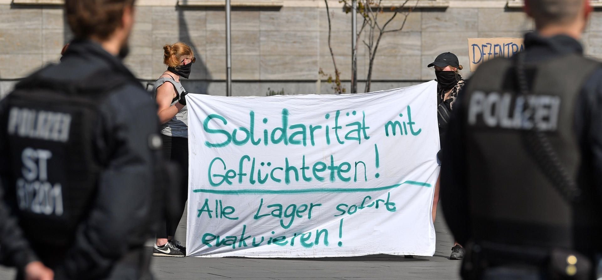 Polizisten beobachten eine Kundgebung in Halle. Die rund 50 Teilnehmer demonstrieren für eine Schließung der zentralen Erstaufnahme für Geflüchtete in Halberstadt.