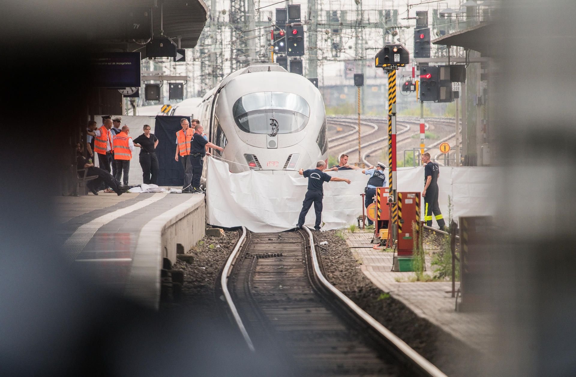 Der Tatort im Frankfurter Hbf: Polizisten und Feuerwehrleute spannen eine weiße Plane als Sichtschutz vor einen ICE.