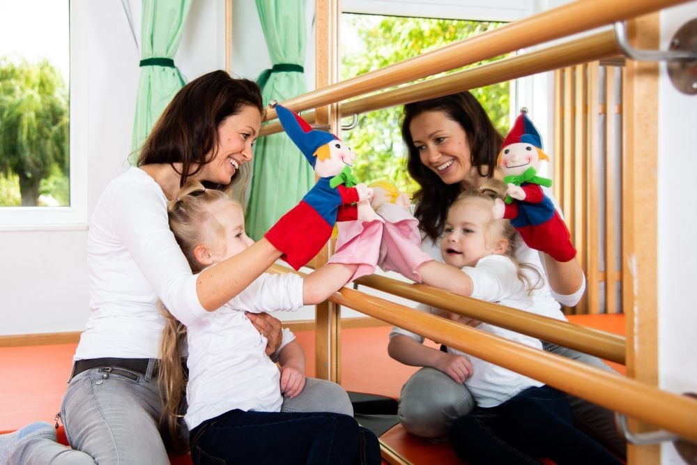 Kathleen Wallschläger, Leiterin der Förderstelle, und ein Mädchen spielen mit Handpuppen. Die Übung soll die Konzentrationsfähigkeit stärken.