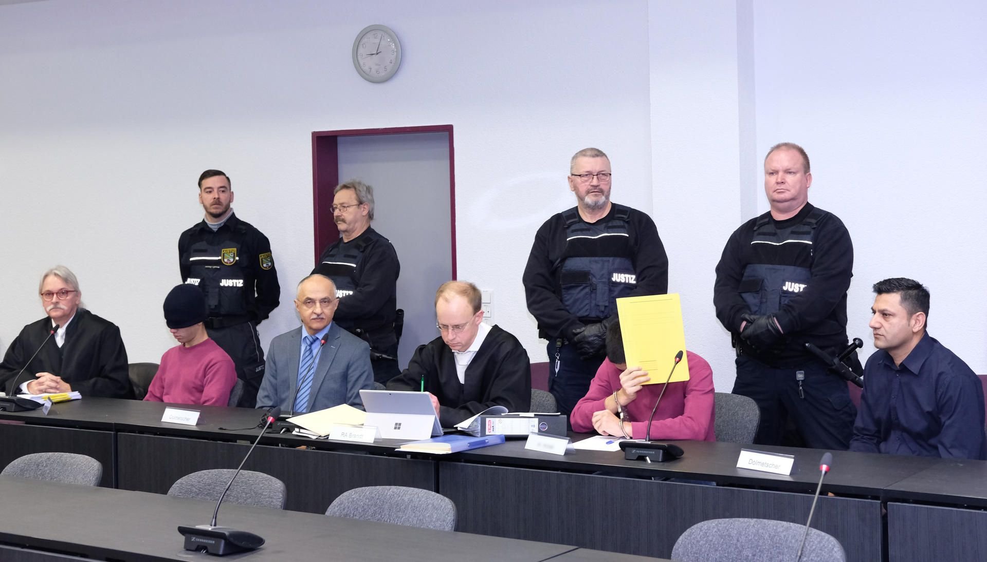 Die wegen Körperverletzung mit Todesfolge Angeklagten (2.v.l) und (3.v.r) sitzen neben Juristen und Dolmetschern im Dessauer Landgericht auf der Anklagebank. (Archivbild)