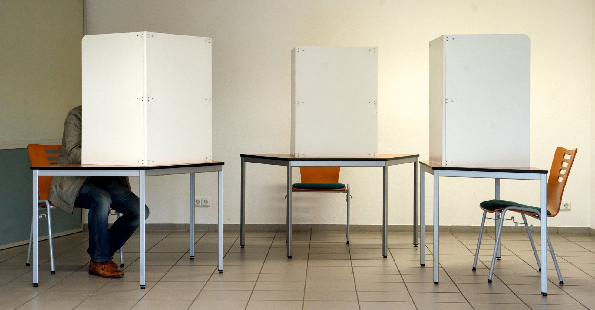 Ein einzelner Mann sitzt in einer von drei Wahlkabinen in Lutherstadt Wittenberg und gibt seine Stimme zur Bundestagswahl ab.