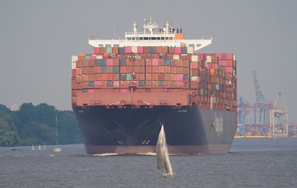 Ein Segelboot ist auf der Elbe vor dem Containerschiff einer Reederei in Hamburg.