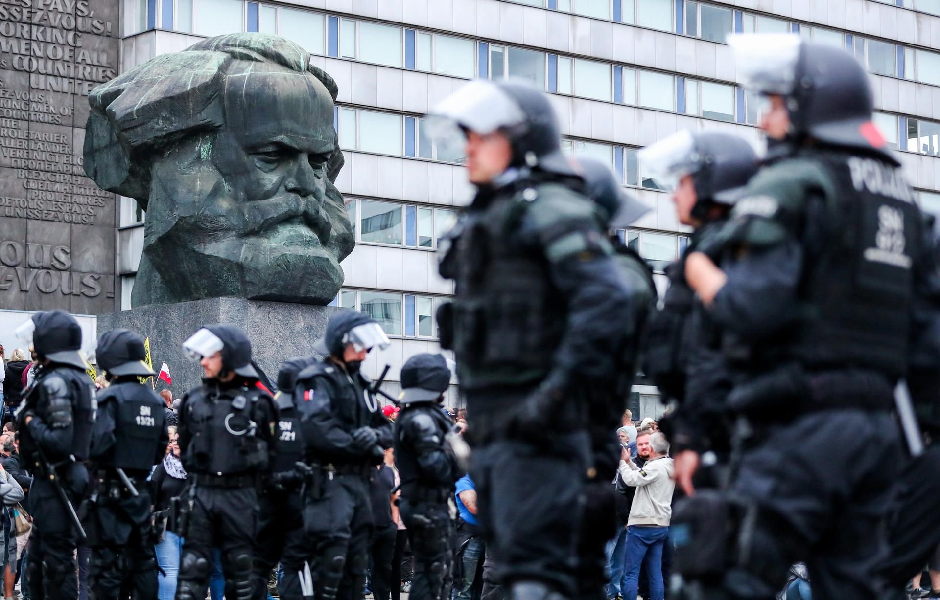 Vor dem Karl-Marx-Denkmal warten Polizisten auf ihren Einsatz in Chemnitz.
