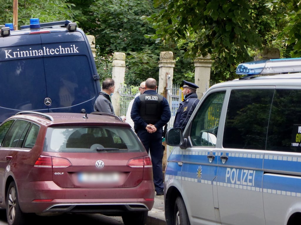 Polizeibeamte unterhalten sich vor einem Wohnhaus in Werdau in dem eine Mutter und ihr Kind getötet wurden.