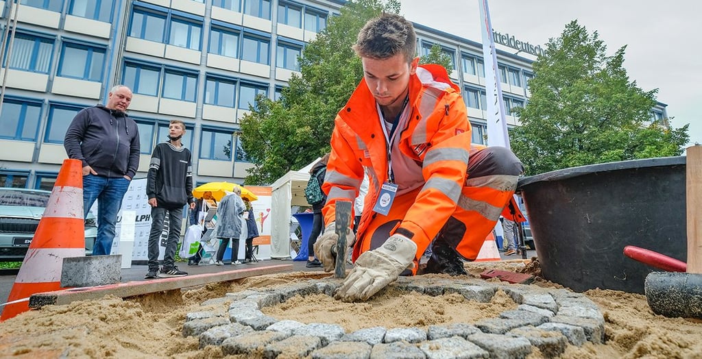 Chris Prause (Firma Strabag) legt aus Natursteinen ein Mosaik.