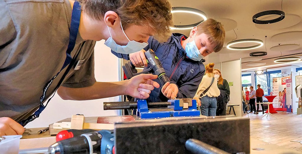 Christopher Rothe (Firma Kleusberg) erklärt Dominik (14) den Umgang mit Holz.