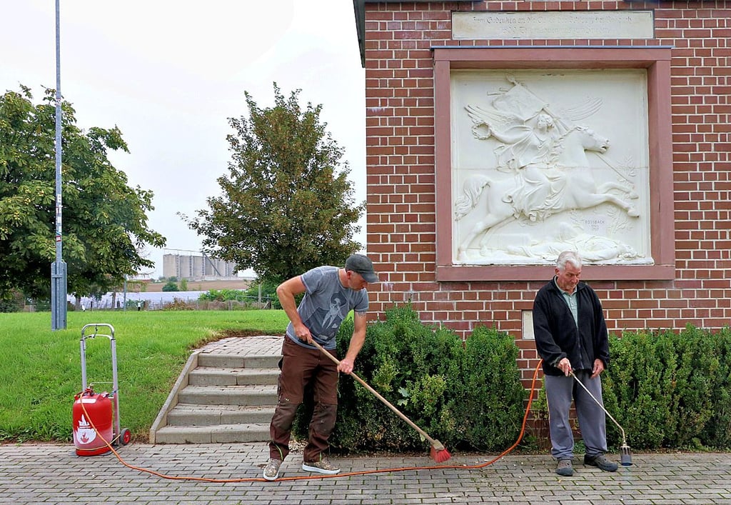 Mario Grunicker (links) und Ronald Bär kümmern sich um die Unkrautbeseitigung am Roßbach-Denkmal in Reichardtswerben.