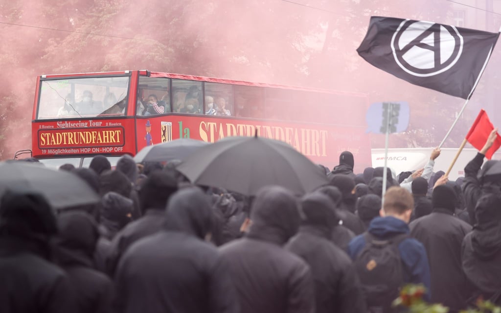 Gäste einer Stadtrundfahrt betrachten Teilnehmer der „LinX“-Demonstration im Dunst der Pyrotechnik.