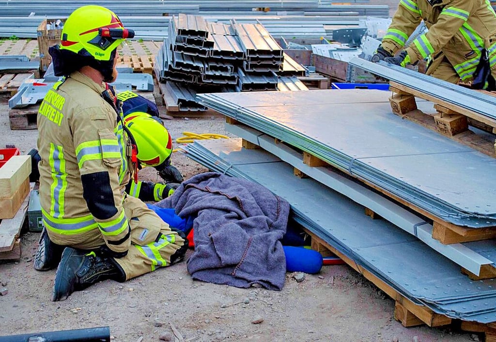 Zwei Feuerwehrmänner betreuen den eingeklemmten Lehrling. Mittels Hebekissen wird er befreit.