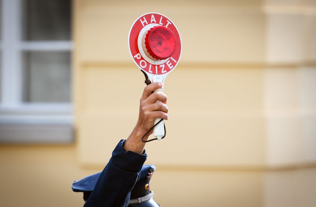 Ein Polizist hält eine Winkerkelle in der Hand.