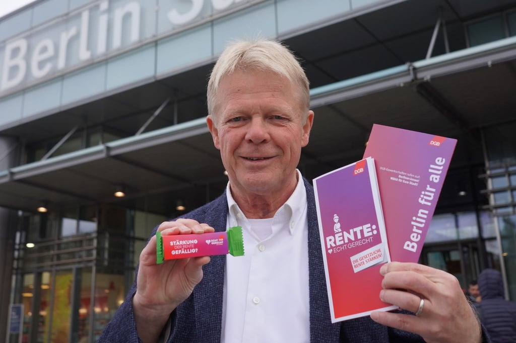 Der DGB-Bundesvorsitzende Reiner Hoffmann verteilt am Bahnhof Südkreuz Flyer zum Thema "Rente".