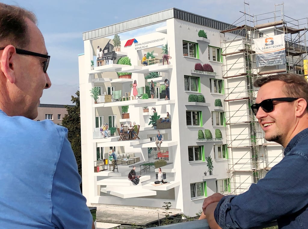 Auftraggeber Peter Arlt, Geschäftsführender Vorstand der Wohnungsgenossenschaft, und Künstler Marco Brzozowski begutachten auf der Annenbrücke in Bernburg das Meisterwerk am Giebel des Plattenbaus.