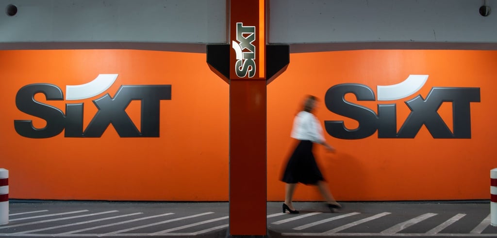 Eine Frau geht am Logo des Autovermieters Sixt vorbei.