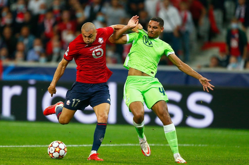 Maxence Lacroix vom VfL Wolfsburg (r) kann sich im Kampf um den Ball nicht gegen Burak Yilmaz vom OSC Lille durchsetzen.