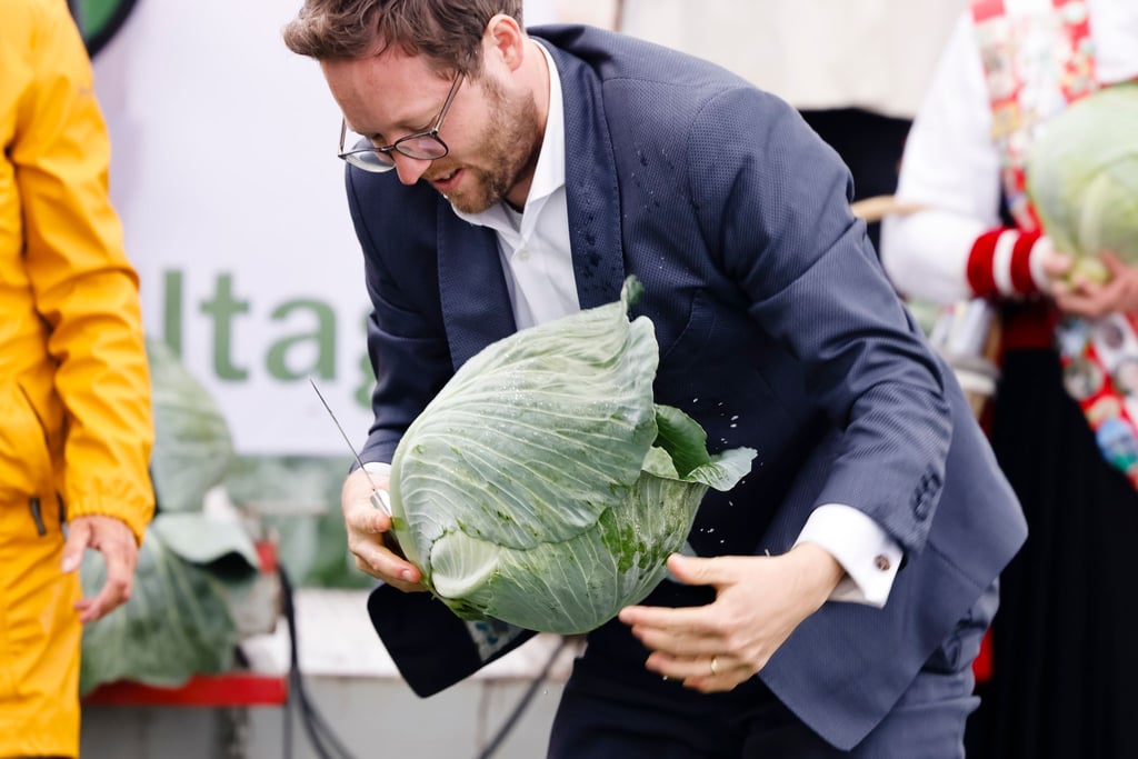 Agrarminister Jan Philipp Albrecht hält ein Messer und einen Kohlkopf in den Händen.