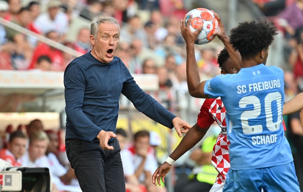 Freiburgs Trainer Christian Streich (l) recht sich bei einer Szene im Spiel beim FSV Mainz auf.