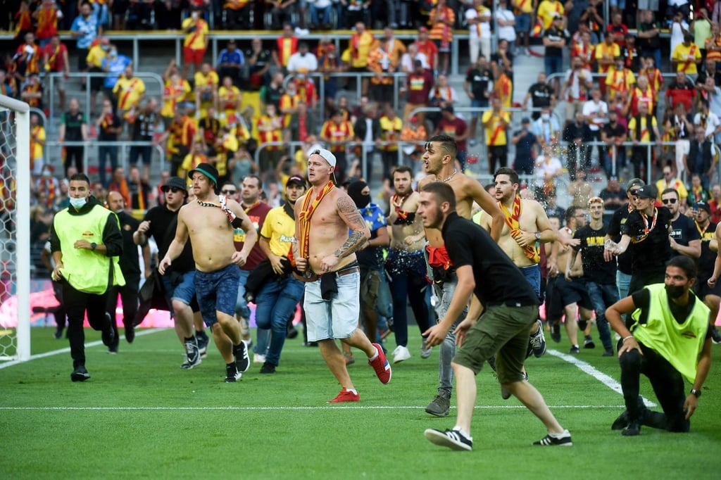 Fans von RC Lens und OSC Lille stürmen auf das Spielfeld des Stade Bollaert-Delelis in Lens.