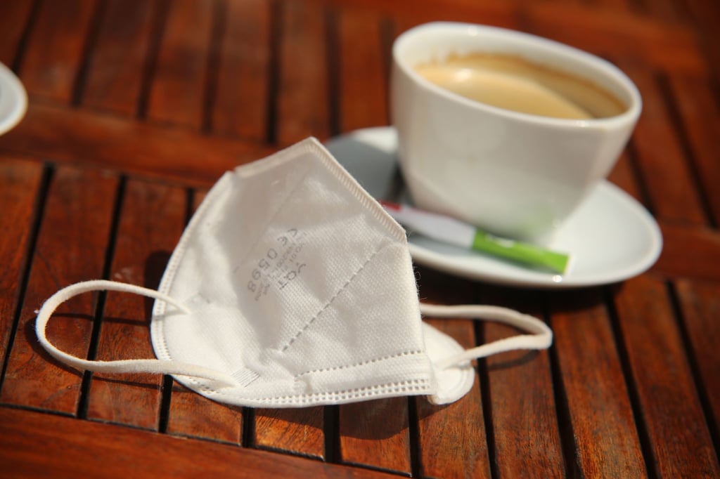 Eine FFP2-Maske liegt neben einer Tasse Kaffee auf einem Tisch. (Archivbild)
