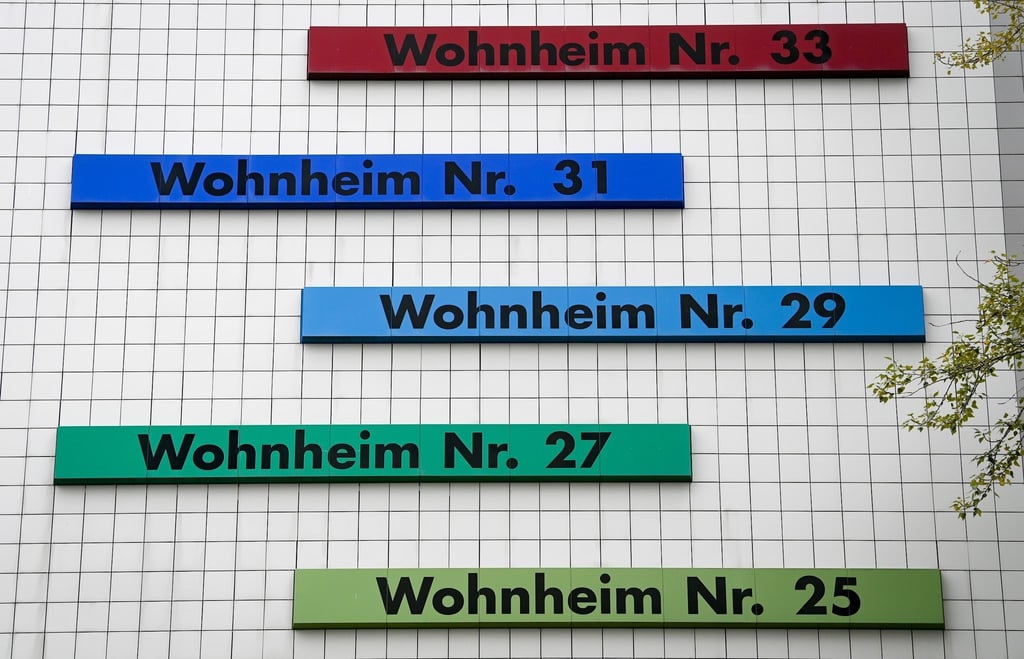 Verschiedenfarbige Schilder weisen den Weg zu den Eingängen in einem Studentenwohnheim.