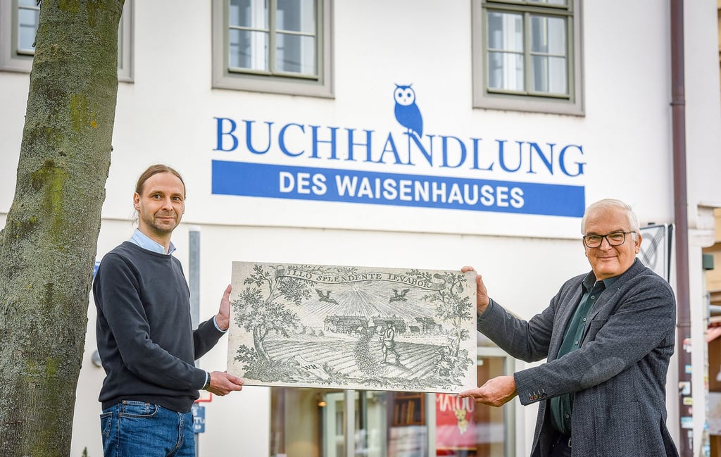 Die Buchhandlung des Waisenhauses hat ihren Namen zurück. Das freut Inhaber Nils Wagner (l.) und Stiftungsdirektor Thomas Müller-Bahlke, der einen Kupferstich mit dem Signet der Buchhandlung mitgebracht hat.