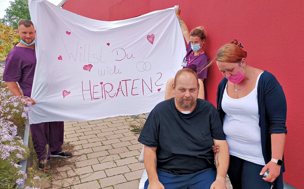 Während Katharina Pöschel von Andreas Hahnen den Heiratsantrag erhält, halten Pflegemitarbeiter der Quedlinburger Intensivstation das Laken mit der Aufschrift "Willst du mich heiraten" in die Höhe.