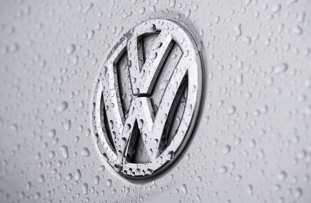 Regentropfen perlen auf einem Volkswagen Logo bei einem VW-Händler.