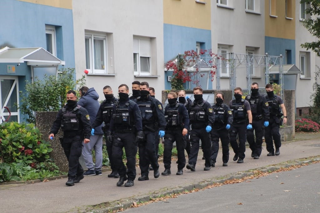 Polizisten durchsuchen die Muldestraße in Halle-Neustadt.