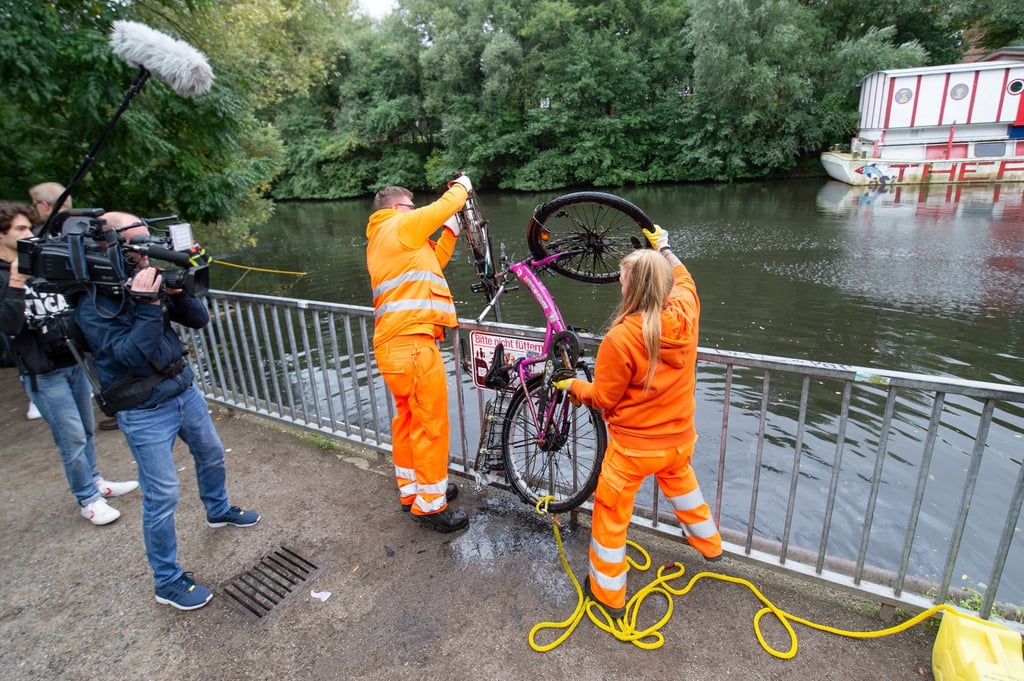 Mitarbeiter der Stadtreinigung heben zwei Fahrräder aus dem Wasser des Isebekkanals.