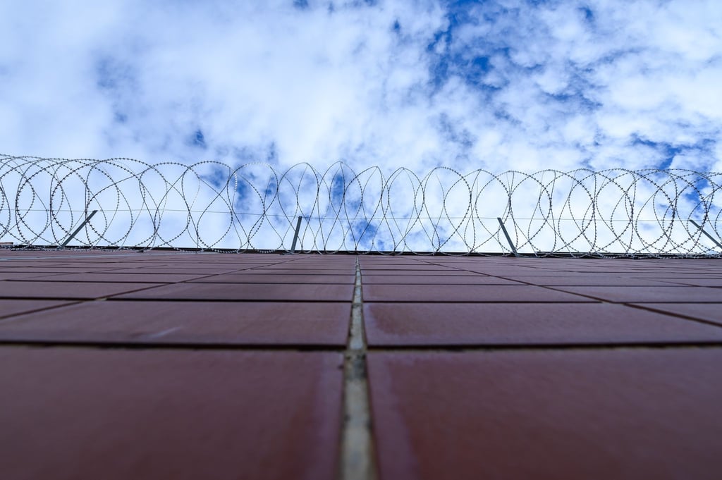 Stacheldrahtzaun an der Mauer einer Justizvollzugsanstalt.