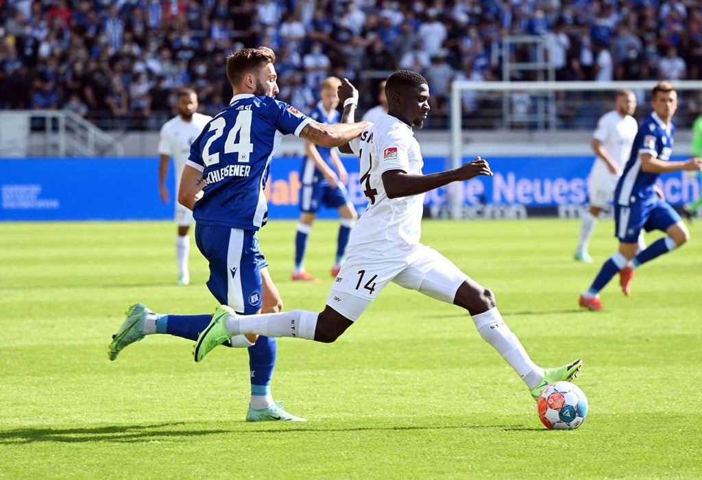 Der Karlsruher Fabian Schleusener (l) und St. Paulis Afeez Aremu kämpfen um den Ball.